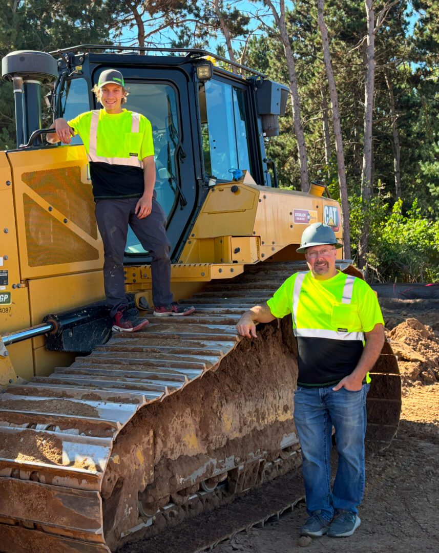 Two construction workers standing by bulldozer