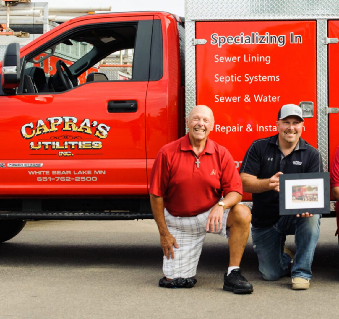 Two men kneeling beside red utility truck